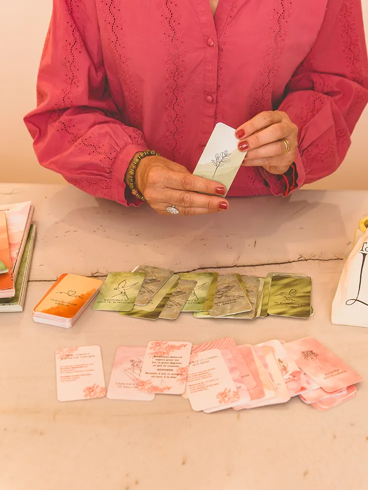 Femme en chemise rose triant des cartes vertes et roses étalées sur une table - collections Traitement et Rémission Toujours L pour femme atteinte de cancer