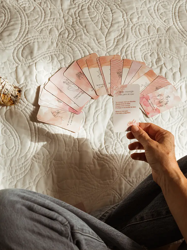 Femme éventail de cartes roses en main sur un lit, avec un bâton de sauge à côté - collection Traitement en vente sur Toujours L, site pour femme atteinte de cancer