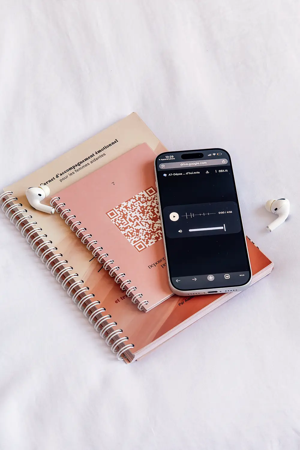 Carnets aux tons terracotta avec QR code, écouteurs et smartphone affichant un audio - collection Aidantes en vente sur Toujours L, site pour femme aidante d'une proche atteinte de cancer
